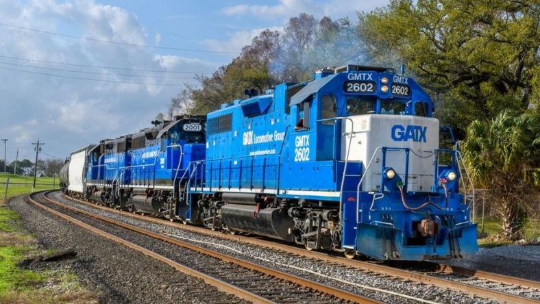 Blue GATX freight locomotives pulling railcars on a U.S. rail line