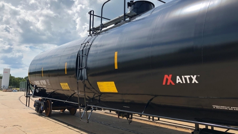 Black freight rail tank car with ladder and safety markings on railway track